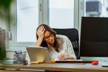 Genç stajyer yeni göreviyle ilgili zorluklar yaşıyor. Dosyaya bakarken yorgun ve şaşkın görünüyor.