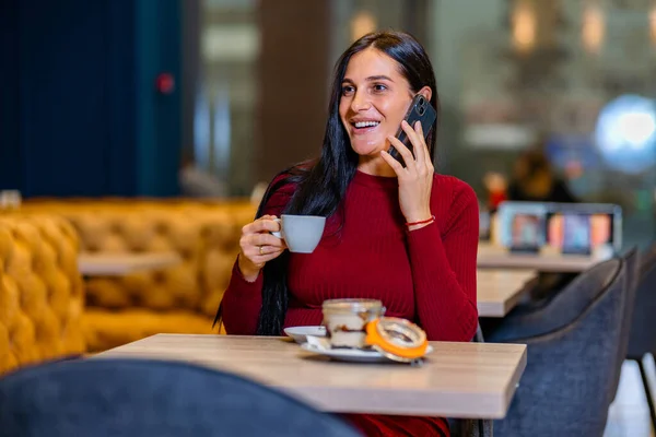 Happy woman smiling, drinking coffee and making a phone call. Woman in business hold a coffee cup in her hand making a business call