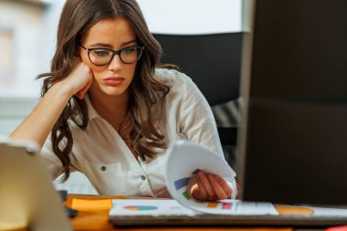 Genç stajyer yeni göreviyle ilgili zorluklar yaşıyor. Dosyaya bakarken yorgun ve şaşkın görünüyor.