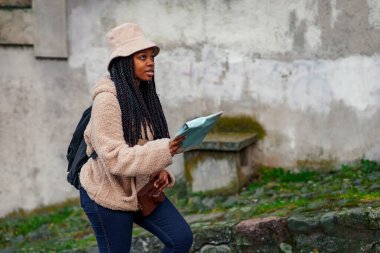 Afro-Amerikalı turist önümüze bakıyor, gezgin turist turist turunda gezinirken ve yerleri kontrol ederken harita kullanıyor.