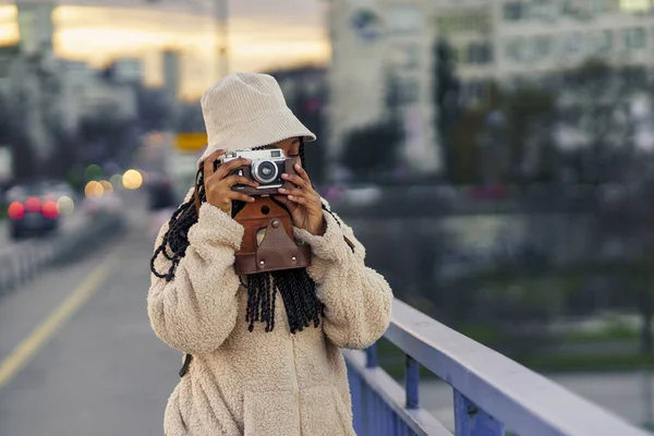Büyük bir şehirde gezen Afrikalı Amerikalı kadın tatil tatili için yeni bir şehre gitti. Kameraya bakıp fotoğraf çekiyor.