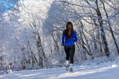 Karlı kış gününde doğada koşan sporcu kadın. Kış fitness konsepti.