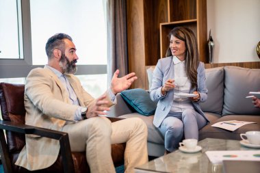 Olgun bir iş adamı ve genç bir meslektaşı yeni projelerini tartışmak için bir kağıt döküman kullanıyorlar..