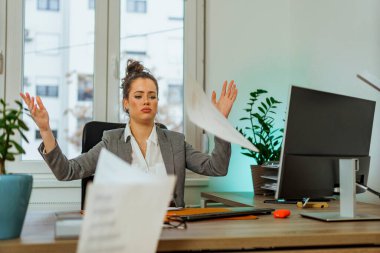 A young business woman throws her papers as a sign of relief in the air after a successfully completed job