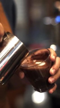 Barista 'nın sıcak sütlü latte bardağında köpük sanatı yaptığı yakın plan.