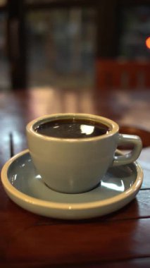 Bir fincan sıcak kahve ya da ahşap masa ve arka planda çay.