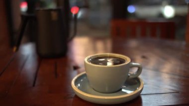 Bir fincan sıcak kahve ya da ahşap masa ve arka planda çay.