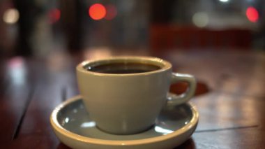 Bir fincan sıcak kahve ya da ahşap masa ve arka planda çay.