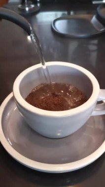 Kahve yapmak için bardağa sıcak su döken biri.