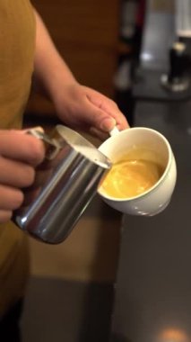 Barista 'nın bir fincan sütlü sütlü sütlü sütlü kahve üzerinde köpük sanatı yaptığı yakın plan.