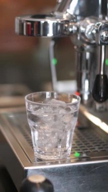 Buzlu Americano kahvesi yapmak için kahve makinesinde buzlu bir bardak suya espresso dökmek.