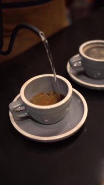 Kahve yapmak için bardağa sıcak su döken biri.