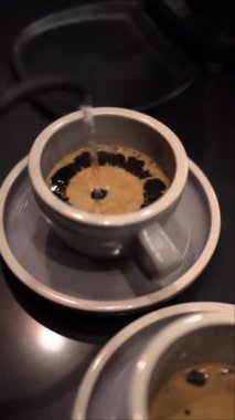 Kahve yapmak için bardağa sıcak su döken biri.