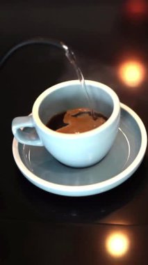 Yüksek açı, kahve yapmak için bardağa sıcak su döken kişinin yakın görüntüsü.