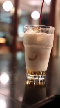 Bokeh arkaplanlı bir bardak süte espresso döküyorum.