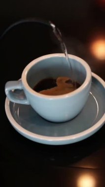 Yüksek açı, kahve yapmak için bardağa sıcak su döken kişinin yakın görüntüsü.