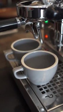 Kahve makinesinden iki fincana akan taze espresso görüntülerini kapat.