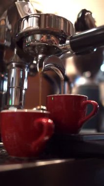 Kahve makinesinden iki kırmızı fincana akan taze espresso görüntülerini kapat.