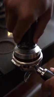 Kahveci espresso yapmak için portafilter üzerine kahve dolduruyor.