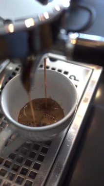 Kahve makinesinden beyaz fincana akan taze espresso görüntülerini kapat.