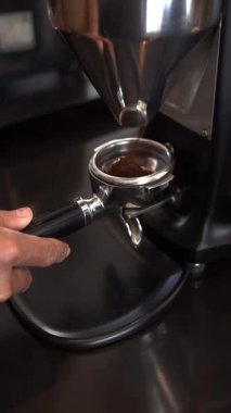 Barista espresso yapmak için kapı filtresini kahve telvesiyle doldurur.