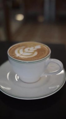 Beyaz fincan ve çay tabağında köpüklü kahve.