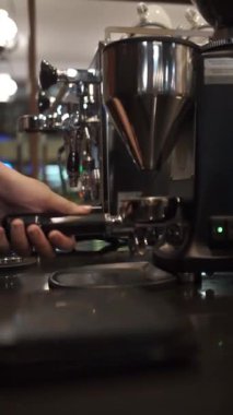 Barista espresso yapmak için kapı filtresini kahve telvesiyle doldurur.