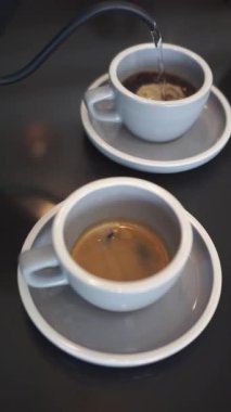 Sıcak bir içecek, kahve ya da çay yapmak için iki fincana sıcak su döken birine yakın durun.