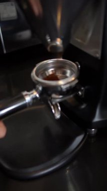 Barista espresso yapmak için kapı filtresini kahve telvesiyle doldurur.