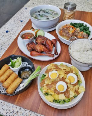 Kızarmış tavuk, börek, sebze çorbası ve salata dahil çeşitli Asya yemekleri.