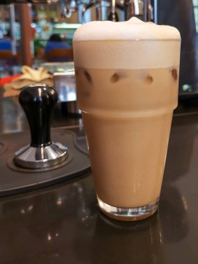 Kafe tezgahında bir bardak buzlu kahve.