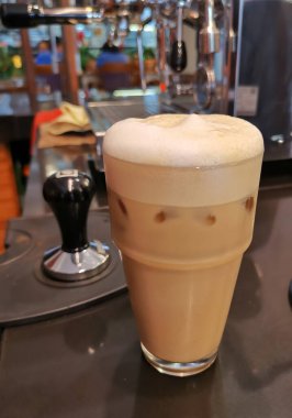 Kafe tezgahında bir bardak buzlu kahve.