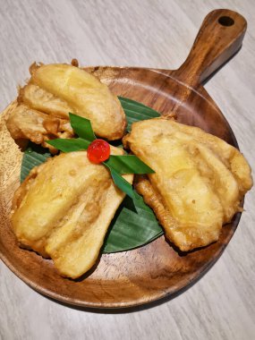 Kızarmış muz, kiraz ve pandan yapraklı ahşap tepside.