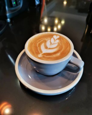 Kafe tezgahında köpüklü bir fincan sıcak latte.
