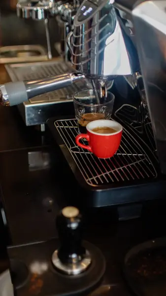 Espresso makinesi iki kırmızı fincana espresso döküyor.