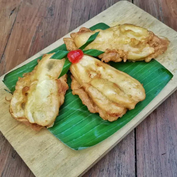 Kızarmış muz, kiraz ve pandan yapraklı ahşap tepside.