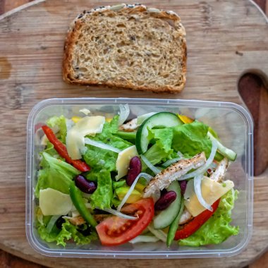 Sebze salatası masanın üstünde, üzerinde bir dilim ekşi ekmek var.