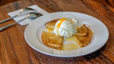 Krep Suzette veya portakal soslu krep ve vanilyalı dondurma. Üç katlanmış krep beyaz bir tabakta serpiştiriliyor, parlak portakal sosuyla serpiştiriliyor. Ortasında bir kepçe vanilyalı dondurma duruyor, üstünde de portakal aromalı garnitür.