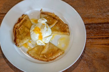 Krep Suzette veya portakal soslu krep ve vanilyalı dondurma. Üç katlanmış krep beyaz bir tabakta serpiştiriliyor, parlak portakal sosuyla serpiştiriliyor. Ortasında bir kepçe vanilyalı dondurma duruyor, üstünde de portakal aromalı garnitür.