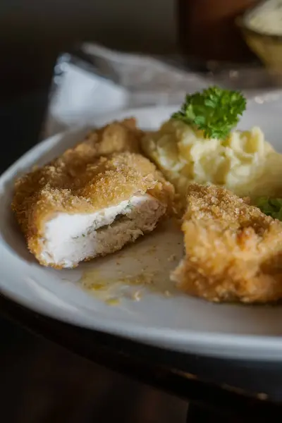 Tavuk Kiev. Kızarmış tavuk filetosu ve yanında taze maydanozla süslenmiş kremalı patates püresi..