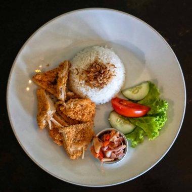 Tavuklu pilav, sebze ve sambal matah beyaz tabakta.