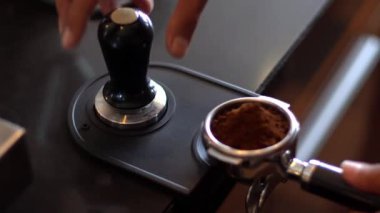 Barista, kahve telvesini filtreye bastırmak için kahve karıştırıcı kullanıyor.