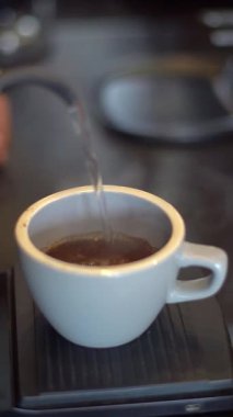 Kahve yapmak için bardağa sıcak su döken biri.