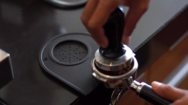 Barista, kahve telvesini filtreye bastırmak için kahve karıştırıcı kullanıyor.