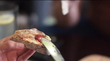 Kahverengi zanaatkar mayalı ekmeğin üzerine tereyağı ve çilek reçeli koy.