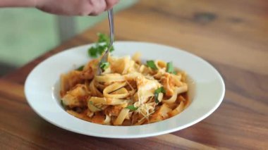 Çatalla makarna yiyen kişi.