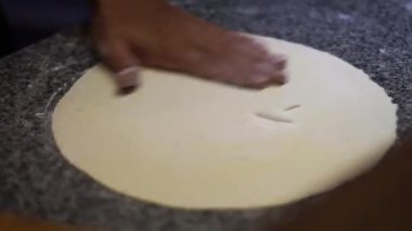 Hamuru mermer yüzeyde tahta bir oklavayla düzleştir.