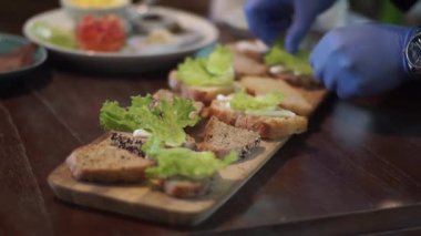 Tahta servis tahtasında kahverengi ekşi ekmek ve sebzeden sandviç yapıyorum.