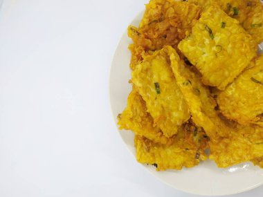 Tempe Mendoan, beyaz arka planda izole edilmiş, dilimlenmiş pırasa ve baharat karışımıyla un hamuru ile kaplanmış geleneksel Endonezya kızarmış gıdası.