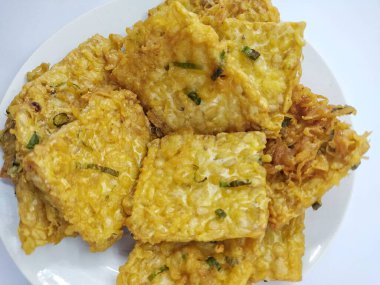 Tempe Mendoan, beyaz arka planda izole edilmiş, dilimlenmiş pırasa ve baharat karışımıyla un hamuru ile kaplanmış geleneksel Endonezya kızarmış gıdası.